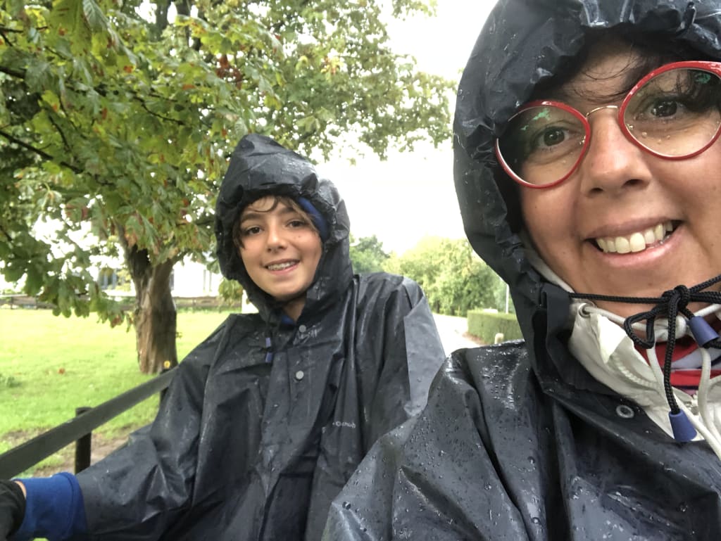Coppia sorridente sotto la pioggia con mantelle impermeabili in un parco vicino ad Amsterdam, Paesi Bassi.